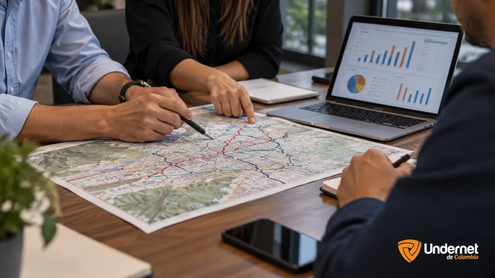 Equipo de trabajo analiza en una mesa un mapa de rutas impreso y gráficas de datos de una flota de vehículos